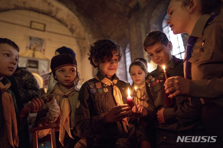 [하르키우=AP/뉴시스] 25일(현지시간) 우크라이나 하르키우에서 열린 성탄 예배에서 우크라이나 스카우트 단원들이 베들레헴 평화의 빛을 들고 있다. 2022.12.26. 