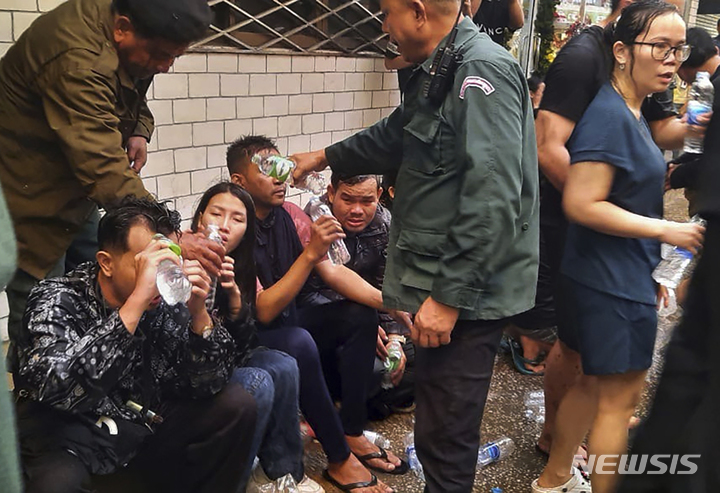[포이펫=AP/뉴시스] 28일(현지시간) 태국과 국경을 맞대고 있는 캄보디아 포이펫에 있는 카지노 호텔에서 화재가 발생해 현지 경찰이 대피한 사람들에게 물을 건네고 있다. 현지 경찰은 이 화재로 지금까지 최소 11명이 숨지고 30명이 다쳤다고 밝혔다. 2022.12.29.
