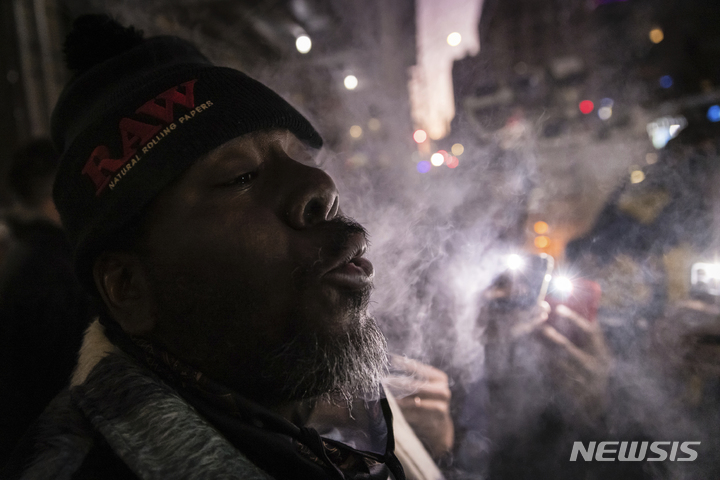 [뉴욕=AP/뉴시스] 29일(현지시간) 미 뉴욕주 뉴욕의 기호용 마리화나 판매점 앞에서 한 남성이 마리화나를 피우고 있다. 뉴욕주의 허가를 받아 주 최초로 마리화나 판매점을 연 비영리단체 '하우징 웍스'(Housing Works)는 당분간 휴무 없이 주 7일 운영한다고 밝혔다. 2022.12.30.