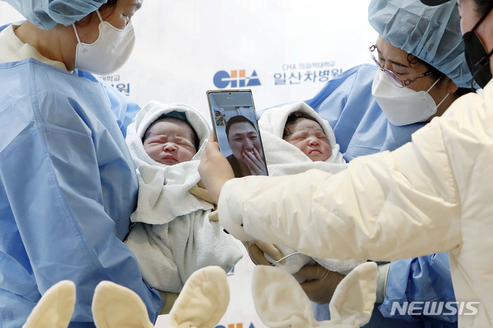[고양=뉴시스] 최동준 기자 = 2023년 새해 첫 아기가 지난 1월1일 0시경 경기 고양시 일산 차병원에서 태어났다. 엄마 김현정 씨(40세), 아빠 장동규 씨(42) 사이에서 태어난 쌍둥이 여아 짱순이(태명, 왼쪽, 3.09kg), 남아 짱짱이(태명, 3,32kg)가 친할머니 정윤자(왼쪽) 씨, 외할머니 문상순 씨 품에 안겨 있다. 코로나19 감염으로 병원을 오지 못 한 아빠 장동규 씨가 영상으로 아기를 보며 감격스러워하고 있다. 2023.01.01. photocdj@newsis.com