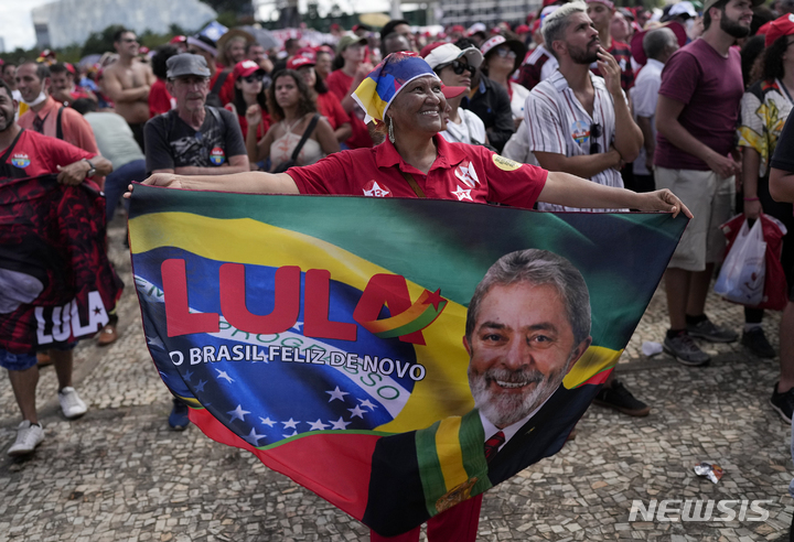 [브라질리아=AP/뉴시스] 1일(현지시간) 브라질 수도 브라질리아의 플라날토궁 밖에 루이스 이나시우 룰라 다시우바 대통령의 지지자들이 깃발을 들고 환호하고 있다. 룰라 대통령은 이날 의회에서 취임 선서를 하고 공식 4년 임기를 시작했다. 2023.01.02.