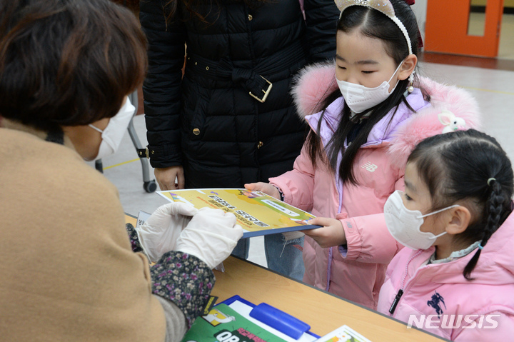 [울산=뉴시스] 배병수 기자 = 울산지역 초등학교 신입생 예비소집일인 지난달 3일 오전 울산 중구 울산초등학교에서 예비 초등학생이 교사로부터 학교 책자를 전달받고 있다. 2023.02.27. bbs@newsis.com.
