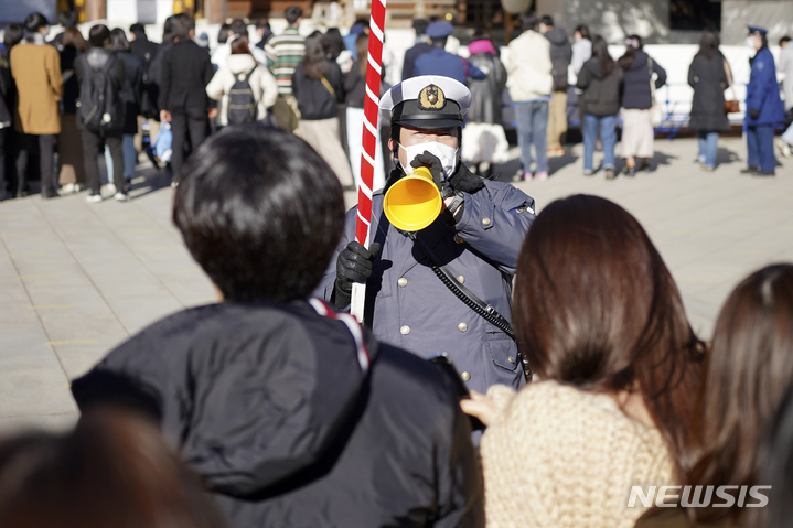 [도쿄=AP/뉴시스] 3일 일본 도쿄의 메이지 신궁에서 한 경찰관이 '하츠모데'를 위해 신사를 찾은 방문객들을 안내하고 있다. '하츠모데'는 새해에 처음으로 신사를 참배하는 행사로 사람들은 신에게 지난 1년 동안 돌봐주신 것에 감사하고 새해의 평안을 빈다. 2023.01.03. 