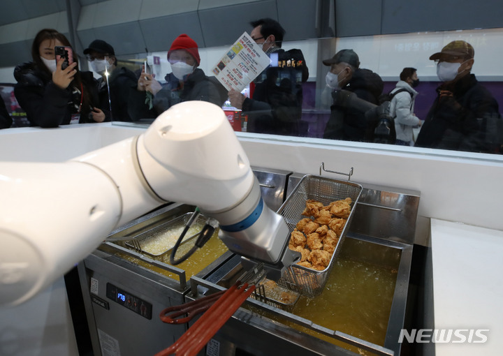 [서울=뉴시스] 조수정 기자 = 지난 1월5일 서울 강남구 코엑스에서 개막한 '제68회 프랜차이즈 창업박람회'에서 참관객들이 바른치킨의 조리 로봇 시연을 보고 있다. 기사 내용과 직접적 관련 없음. 2023.01.05. chocrystal@newsis.com