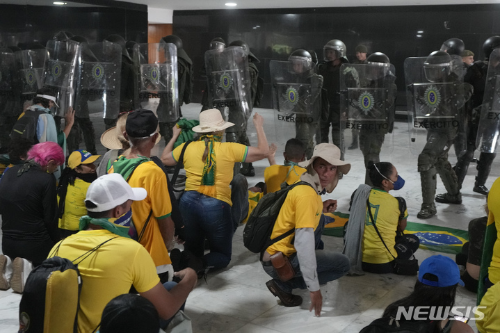 [브라질리아=AP/뉴시스]지난 1월8일(현지시간) 브라질 수도 브라질리아에서 자이르 보우소나루 전 대통령을 지지하는 시위대가 루이스 이나시우 룰라 다시우바 대통령의 집무실을 점거하고 경찰과 대치하고 있다. 보우소나루는 30일 3개월 간의 미 플로리다 체류를 끝내고 브라질로 귀국, 브라질 정치 현장에서 새 역할 모색에 나선다. 2023.03.30.