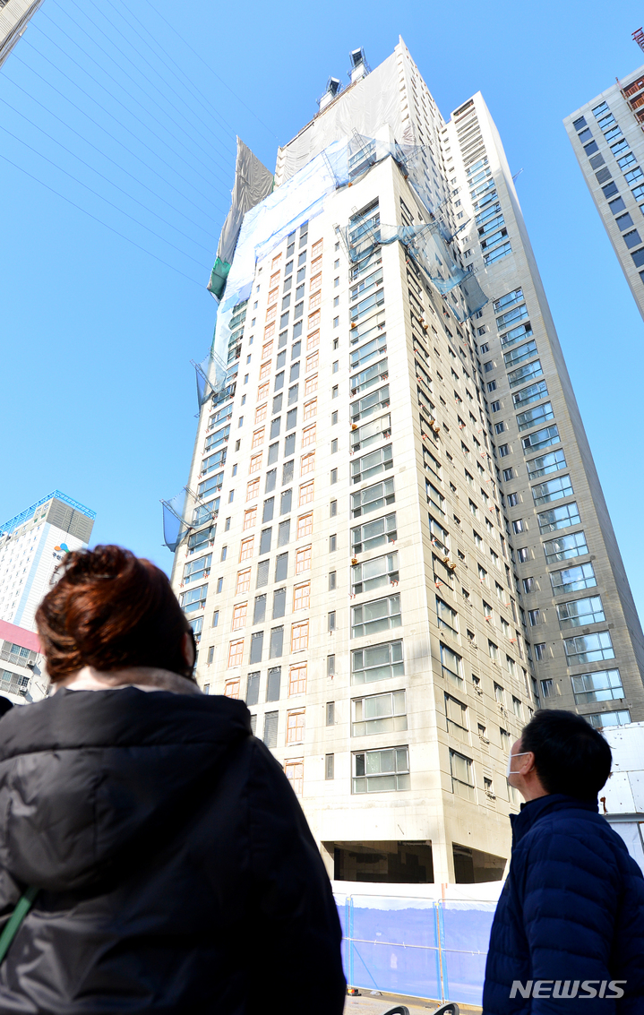 [광주=뉴시스] 김혜인 기자 = 화정아이파크 붕괴 참사 1주기인 11일 오전 광주 서구 화정동 참사현장에서 추모객이 사고가 일어난 아파트를 바라보고 있다.2023.01.11.hyein0342@newsis.com