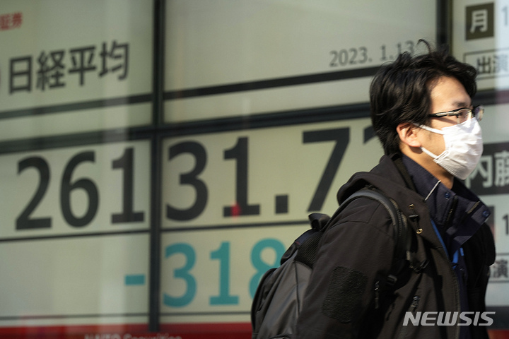 A man walks by monitors showing Japan's Nikkei 225 index at a securities firm in Tokyo, Friday, Jan. 13, 2023. Shares advanced Friday in Asia after news that U.S. consumer inflation slowed last month pushed Wall Street benchmarks higher.(AP Photo/Hiro Komae)
