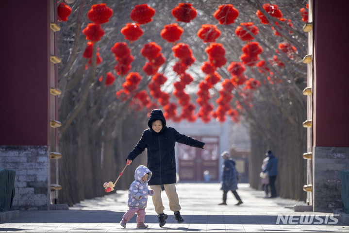 [베이징=AP/뉴시스] 20일 중국 베이징에서 한 여성이 다가오는 춘제를 앞두고 붉은 등으로 장식된 공원길에서 아이와 놀고 있다. 2023.01.20.