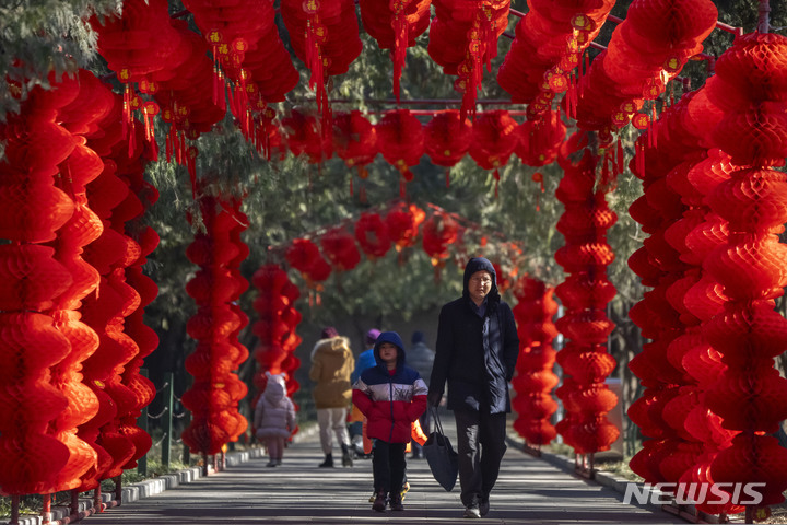[베이징=AP/뉴시스] 20일 중국 베이징의 공원에서 한 남성이 아이와 함께 다가오는 춘제를 앞두고 붉은 등으로 장식된 길을 걷고 있다. 2023.01.20.
