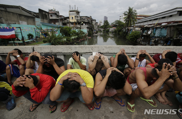 [AP/뉴시스] 필리핀의 두테르테 대통령이 취임한 직후 '마약과의 전쟁'을 선포한 뒤 경찰에 체포된 용의자들이 고개을 묻고 쪼구리고 앉아있다. 취임 100일 뒤인 2016년 10월 초 미국과 유엔, 유럽연합 등은 두테르테 경찰들이 재판없이 3600명이 넘는 용의자들을 무법 처단했다고&nbsp;&nbsp;&nbsp; 비난했다.