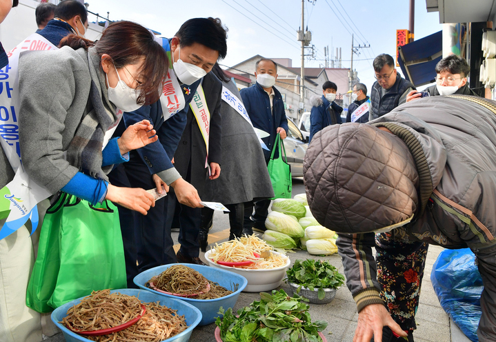 [장성=뉴시스] 김한종 전남 장성군수(왼쪽 두 번째)가 전통시장에서 지역화폐로 나물을 구매하고 있다. (사진=장성군 제공) 2023.01.30. photo@newsis.com *재판매 및 DB 금지