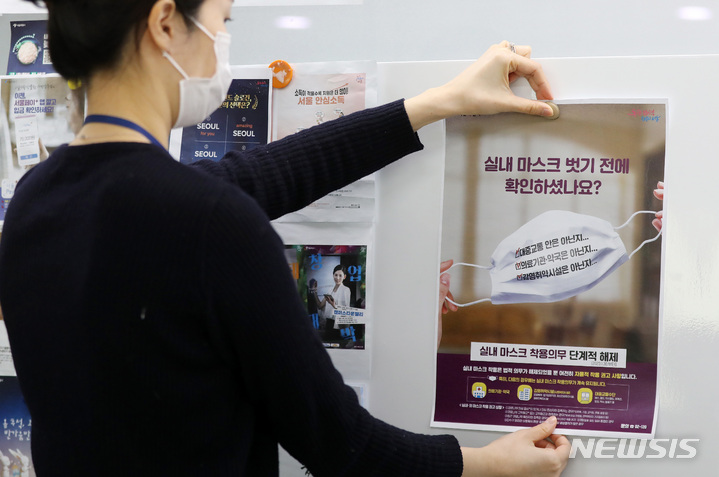 [서울=뉴시스] 백동현 기자 = 지난 30일 오후 서울시청 소통전략팀 사무실에서 직원이 새롭게 제작한 실내 마스크 관련 안내문을 붙이고 있다. 2023.01.31. livertrent@newsis.com