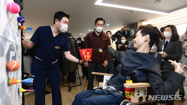 [서울=뉴시스] 고승민 기자 = 오세훈 서울시장이 지난 2023년 2월1일 서울 강동구 중증뇌병변장애인 긴급수시돌봄 한아름 단기거주시설을 방문해 김우솔 씨가 손근육 재활운동하는 모습을 살펴보고 있는 모습. (공동취재사진) 2023.02.01. photo@newsis.com