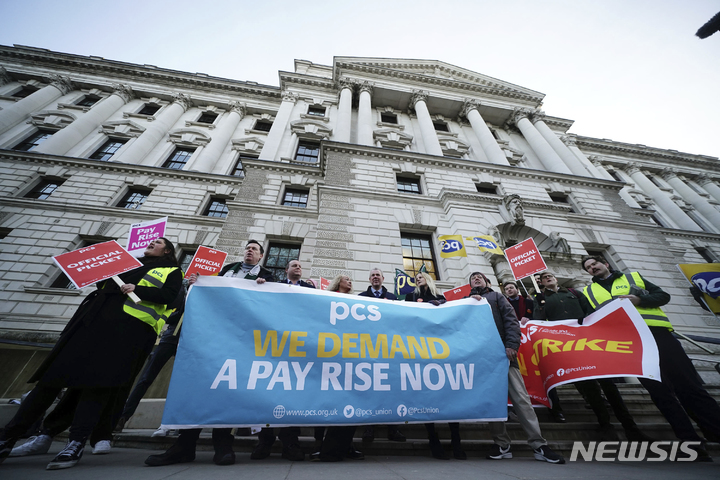 [런던=AP/뉴시스]영국 공공 및 상업 서비스(PCS) 노조원들이 1일 런던 웨스트민스터의 재무부 청사 앞에 임금 인상을 요구하는 현수막을 들고 서 있다. 영국이 1일 10여년 만에 최대의 파업으로 학교 수천 곳의 수업이 부분 또는 전면 폐쇄되고, 열차 운행은 마비되며, 공항들의 항공기 운항은 지연될 것으로 예상된다. 영국 노동조합들은 생활비 위기 속에서 정부에 더 많은 임금 인상을 요구하라는 압력을 강화하기 위해 이날 대규모 파업에 나선다. 2023.2.1