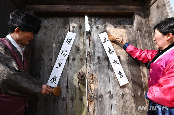 [용인=뉴시스] 김종택 기자 = 절기상 입춘을 이틀 앞둔 2일 오전 경기도 용인 한국민속촌에서 관계자들이 '입춘대길(立春大吉)', '건양다경(建陽多慶)' 등 입춘첩을 붙이고 있다. 2023.02.02. jtk@newsis.com
