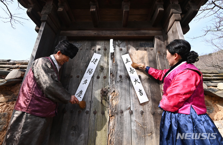 [용인=뉴시스] 김종택 기자 = 절기상 입춘을 이틀 앞둔 2일 오전 경기도 용인 한국민속촌에서 관계자들이 '입춘대길(立春大吉)', '건양다경(建陽多慶)' 등 입춘첩을 붙이고 있다. 2023.02.02. jtk@newsis.com