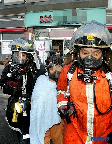 [청주=뉴시스] 2006년 1월10일 전기합선으로 불이 난 충북 청주시 흥덕구 분평동 사우나시설. 유독가스를 마신 이용객이 산소마스크를 쓴 채 소방대원에게 구조되고 있다. (사진=뉴시스 DB) photo@newsis.com&nbsp; *재판매 및 DB 금지