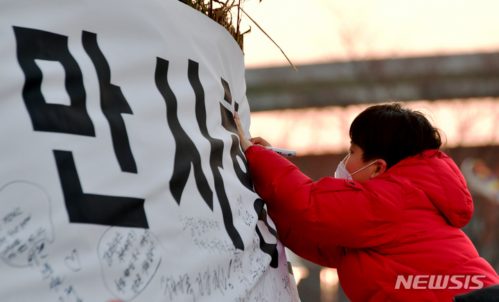 [광주=뉴시스] 이영주 기자 = 정월대보름을 하루 앞둔 4일 오후 광주 남구 고싸움놀이테마파크에서 한 아이가이 달집에 소원을 적고 있다. 2023.02.04.leeyj2578@newsis.com