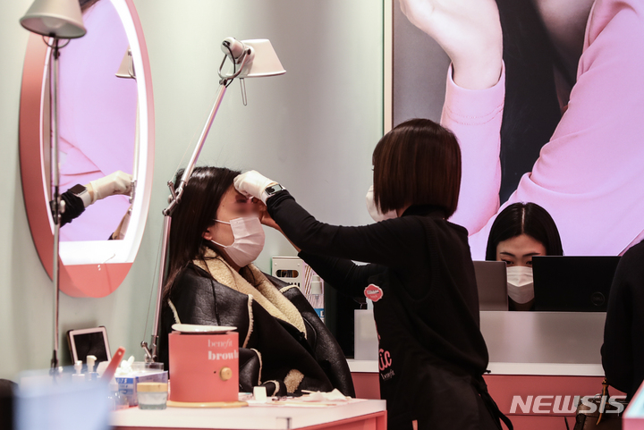 [서울=뉴시스] 김근수 기자 = 실내마스크 일부 해제 첫 주말인 5일 오후 서울 시내의 한 백화점 화장품 가게에서 한 소비자가 제품을 체험하고 있다. 2023.02.05. ks@newsis.com