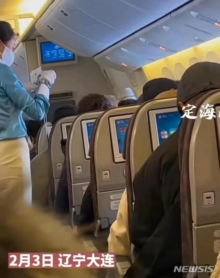 [서울=뉴시스] 지난 3일 중국 랴오닝성 다롄공항에 착륙하기 전 한 대한항공 여객기에서 승무원이 중국 이외 국적 승객들에게 흰색 비표를 나눠주고 있는 모습. <사진출처: 웨이보 캡쳐> 2023.02.09