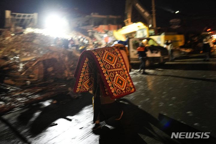 [엘비스탄=AP/뉴시스] 8일(현지시간) 튀르키예 남부 엘비스탄 지진 피해 현장에서 시민이 담요와 매트리스를 들고 이동하고 있다. 2023.02.09.