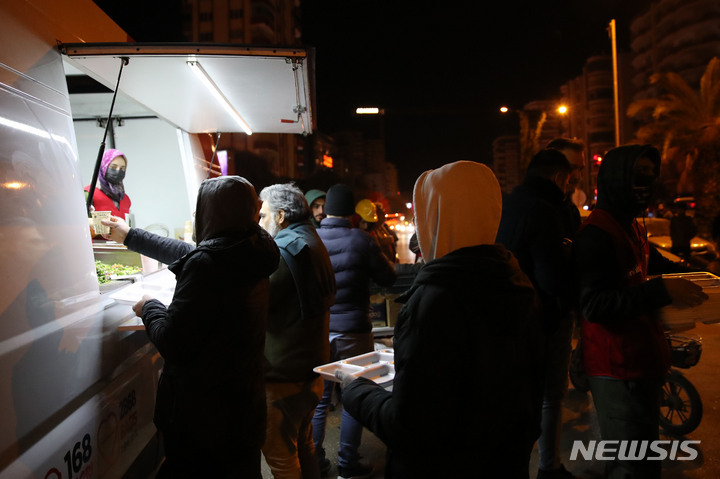 [아다나=뉴시스] 권창회 기자 = 9일 오후(현지시간) 튀르키예 아다나 시내의 지진 구조작업 현장 인근에 이재민들이 구호물품인 음식을 받고 있다. 2023.02.10. kch0523@newsis.com