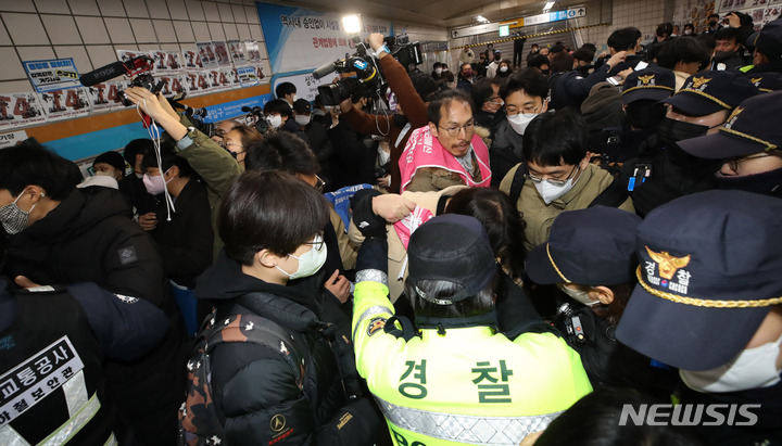 [서울=뉴시스] 조수정 기자 = 전국장애인차별철폐연대(전장연)가 13일 오전 서울 삼각지역 승강장 앞에서 '시민과 함께하는 달보기 운동' 선언 기자회견을 마친 뒤 승강장 바닥에 부착한 선전물이 비가 오면 미끄러우니 떼라는 지하철 공사 측의 요청에 락카로 '미끄럼 주의' 문구를 써놓으려다 제지하는 지하철공사 직원들과 몸싸움을 하고 있다. 전장연은 3월 23일까지 출근길 지하철 타기 선전전을 하지 않고 기획재정부가 3월 국가재정전략회의에서 2024년 정부 예산 가이드라인을 편성할 때 장애인 권리예산이 의미있는 수준으로 반영할 것을 촉구하며 기재부 장관이 적극적으로 대화에 나서기를 기다리겠다고 밝혔다. 2023.02.13. chocrystal@newsis.com