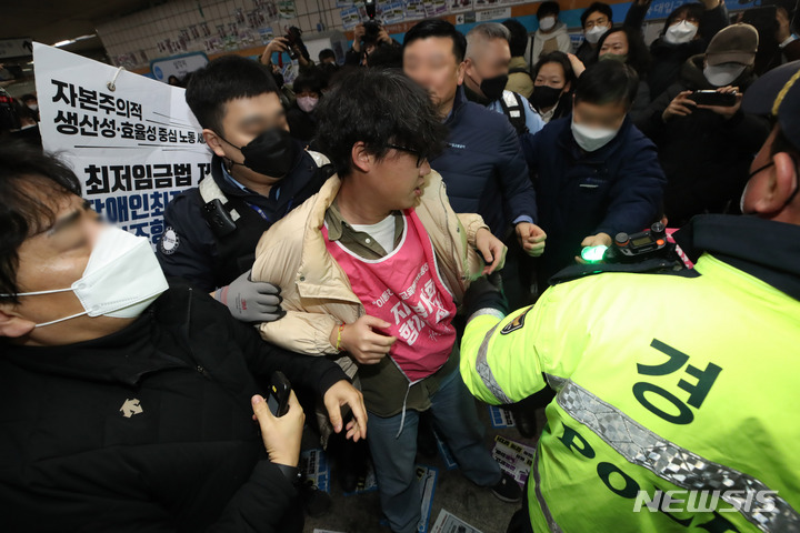 [서울=뉴시스] 조수정 기자 = 전국장애인차별철폐연대(전장연)가 13일 오전 서울 삼각지역 승강장 앞에서 '시민과 함께하는 달보기 운동' 선언 기자회견을 마친 뒤 승강장 바닥에 부착한 선전물이 비가 오면 미끄러우니 떼라는 지하철 공사 측의 요청에 락카로 '미끄럼 주의' 문구를 써놓으려다 제지하는 지하철공사 직원들과 몸싸움을 하고 있다. 전장연은 3월 23일까지 출근길 지하철 타기 선전전을 하지 않고 기획재정부가 3월 국가재정전략회의에서 2024년 정부 예산 가이드라인을 편성할 때 장애인 권리예산이 의미있는 수준으로 반영할 것을 촉구하며 기재부 장관이 적극적으로 대화에 나서기를 기다리겠다고 밝혔다. 2023.02.13. chocrystal@newsis.com