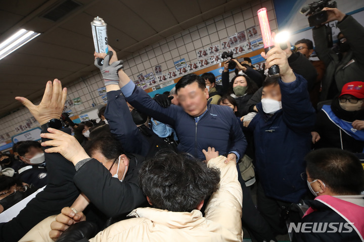 [서울=뉴시스] 조수정 기자 = 전국장애인차별철폐연대(전장연)가 13일 오전 서울 삼각지역 승강장 앞에서 '시민과 함께하는 달보기 운동' 선언 기자회견을 마친 뒤 승강장 바닥에 부착한 선전물이 비가 오면 미끄러우니 떼라는 지하철 공사 측의 요청에 락카로 '미끄럼 주의' 문구를 써놓으려다 제지하는 지하철공사 직원들과 몸싸움을 하고 있다. 전장연은 3월 23일까지 출근길 지하철 타기 선전전을 하지 않고 기획재정부가 3월 국가재정전략회의에서 2024년 정부 예산 가이드라인을 편성할 때 장애인 권리예산이 의미있는 수준으로 반영할 것을 촉구하며 기재부 장관이 적극적으로 대화에 나서기를 기다리겠다고 밝혔다. 2023.02.13. chocrystal@newsis.com