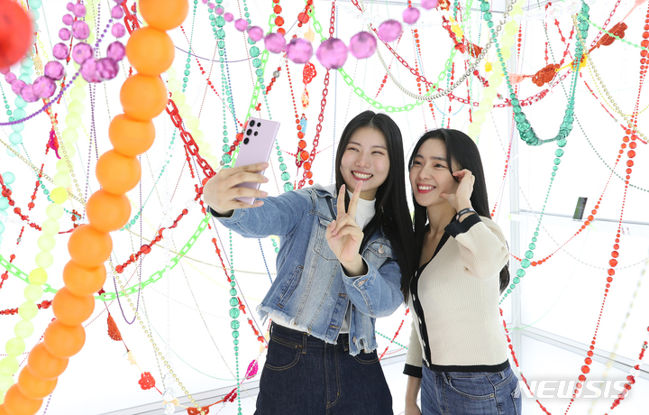 [서울=뉴시스]갤럭시 스튜디오 성수에서 방문객들이 최정화 작가의 작품 '코스모스(Cosmos)'와 함께 '갤럭시 S23 울트라'로 셀피를 촬영하고 있다. (사진=삼성전자 제공)