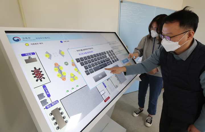 [세종=뉴시스] 21일 정부세종청사 처음으로 자율좌석형 사무공간이 도입된 교육부 디지털교육기획관 직원들이 사무실 앞 단말기(키오스크)에서 자신이 일할 자리를 고르고 있다. (사진=교육부 제공). 2023.02.21. photo@newsis.com *재판매 및 DB 금지