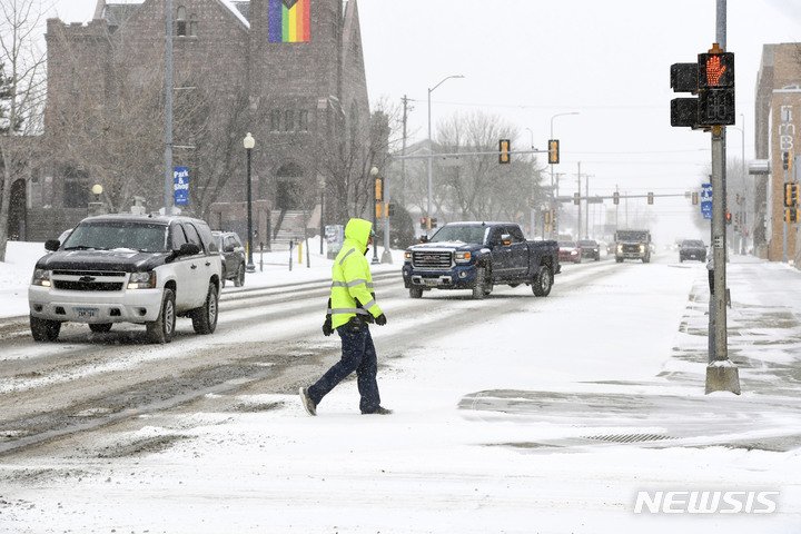 [수폴스=AP/뉴시스] 21일(현지시간) 보행자가 눈 폭풍을 앞두고 사우스타코타 수폴스에서 교차로를 지나고 있다. 2023.02.22.