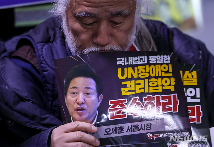 [서울=뉴시스] 정병혁 기자 = 박경석 전국장애인차별철폐연대 공동대표가 27일 오전 서울 중구 지하철 1호선 시청역 승강장에서 열린 서울시 탈시설장애인 전수조사 표적수사 변질 규탄 기자회견에서 피켓을 들고 있다. 2023.02.27. jhope@newsis.com