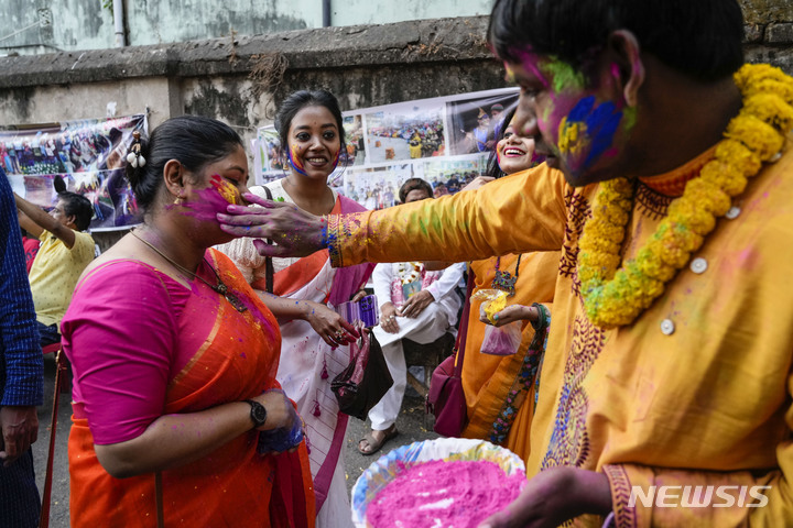 [콜카타=AP/뉴시스] 인도 콜카타에서 4일(현지시간) 크리슈나 복장을 한 장애 청년이 힌두교 홀리제를 맞아 행렬 도중 여성에게 색 가루를 발라주고 있다. 2023.03.07.