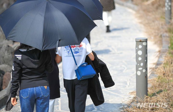 [제주=뉴시스] 우장호 기자 = 추위가 풀려 포근한 날씨를 보이는 지난 5일 오후 제주시 애월읍 한담해안산책로에서 우산을 쓴 관광객들이 가벼운 옷차림으로 걸어가고 있다. 2023.03.05. woo1223@newsis.com