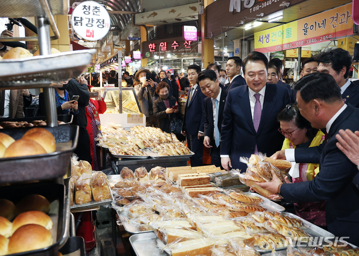 [울산=뉴시스] 전신 기자 = 윤석열 대통령이 9일 울산 남구 신정시장을 찾아 빵집에서 빵을 구입하고 있다. (대통령실통신사진기자단) 2023.03.09. photo1006@newsis.com