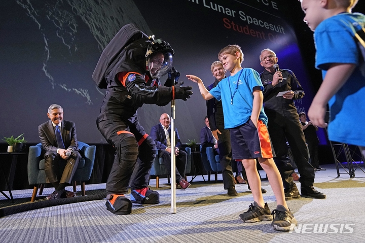 [휴스턴=AP/뉴시스] 15일(현지시간) 미 텍사스주 휴스턴의 존슨우주센터에서 새로운 우주복을 제작한 액시엄 스페이스(AX) 관계자 짐 스타인이 우주복을 입고 아이와 인사하고 있다. 미 항공우주국(NASA)은 이날 '아르테미스3' 임무 수행에 사용할 차세대 우주복 시제품을 선보였다. 2023.03.16.