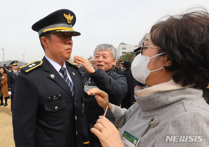 [아산=뉴시스] 배훈식 기자 = 16일 오후 충남 아산시 경찰대학에서 열린 2023년 신임경찰 경위, 경감 임용식에 참석한 임용자 부모님이 임용자에게 계급장을 달아주고 있다. 2023.03.16. dahora83@newsis.com