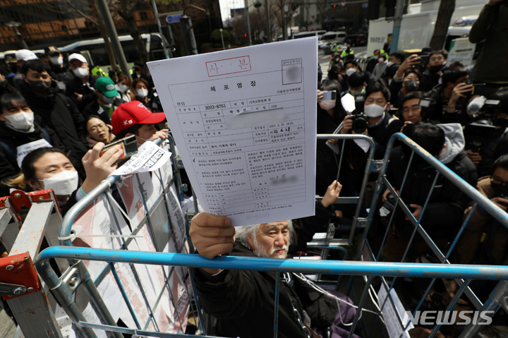 [서울=뉴시스] 조성우 기자 = 박경석 전국장애인차별철폐연대(전장연) 공동상임대표가 17일 오전 서울 종로구 서울경찰청 민원실 앞에서 경찰이 제시한 체포영장을 보여주고 있다. 2023.03.17. xconfind@newsis.com