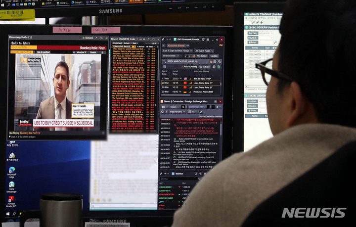[서울=뉴시스] 조성봉 기자 = 20일 오전 서울 중구 하나은행 딜링룸에서 딜러가 유비에스(UBS)의 크레디트 스위스(CS) 인수 관련 뉴스를 시청하며 업무를 보고 있다. 2023.03.20. suncho21@newsis.com
