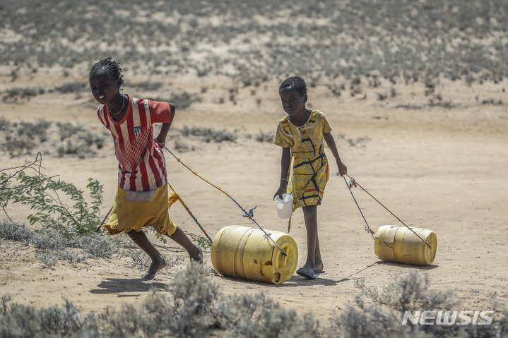 [로모푸트(케냐)=AP/뉴시스]2022년 5월12일 케냐 북부 로모푸트 마을의 한 우물에서 어린 소녀들이 물을 담은 통을 끌고 집으로 돌아가고 있다. 부채에 시달리는 동시에 사이클론, 가뭄, 폭염 등 극단적 기상현상으로 인한 손실과 피해로 황폐화된 아프리카 국가들이 기후 행동에 투자하는 대신 부채를 탕감하는 것을 고려하기로 합의했다. 2023.3.21