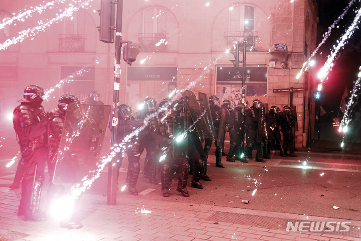 [낭트=AP/뉴시스] 21일(현지시간) 프랑스 낭트에서 시위 진압 경찰이 연금 개혁 반대 시위대가 던지는 불꽃을 맞으며 도로 입구를 봉쇄하고 있다. 정년 및 연금 수령 나이를 62세에서 64세로 올리는 것을 골자로 한 연금 개혁 법안이 헌법위원회의 승인과 에마뉘엘 마크롱 대통령의 서명만 남겨두게 되면서 쓰레기 수거업자, 정유 노동자 등이 다시 파업에 돌입했다. 2023.03.22.