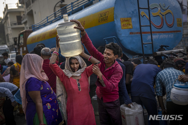 [뉴델리=AP/뉴시스] 세계 물의 날인 22일(현지시간) 인도 뉴델리 주택가의 이동식 물탱크에서 식수를 받은 한 여성이 물통을 머리에 이고 있다. 유엔은 세계 인구의 26%가 안전한 식수를 이용할 수 없고, 46%는 기본적 위생시설 접근이 불가능하다고 보고서를 통해 발표했다. 2023.03.22.
