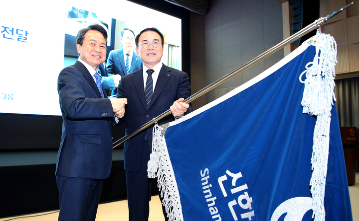 23일 서울 중구 신한금융그룹 본사에서 열린 지주회장 이‧취임식에서 조용병 회장(오른쪽)이 신임 진옥동 회장에게 그룹기를 건네주고 있다. *재판매 및 DB 금지