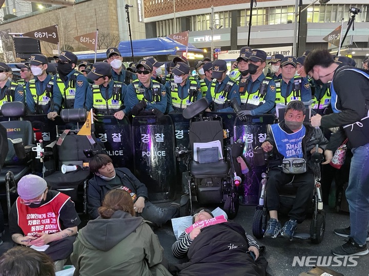 [서울=뉴시스] 임철휘 기자 = 전국장애인차별철폐연대 활동가들이 23일 오후 6시58분께 휠체어로 서울 중구 무교로 입구를 막아서며 경찰과 대치하고 있다. 2023.03.23. fe@newsis.com
