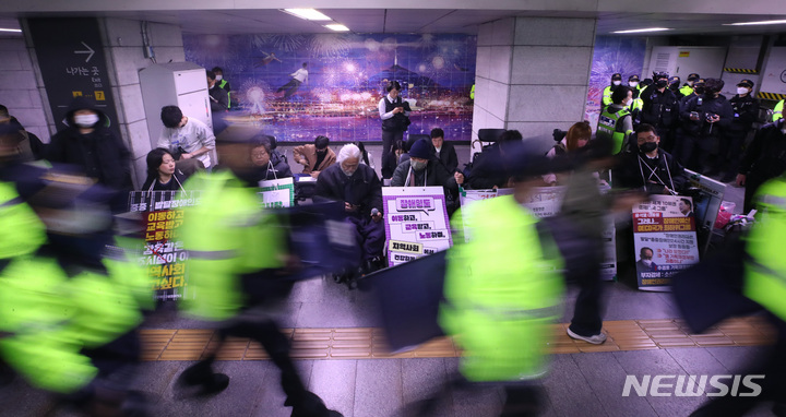 [서울=뉴시스] 김진아 기자 = 전국장애인차별철폐연대(전장연)가 23일 서울 지하철 1호선 시청역에서 오세훈 서울시장 대화 촉구 출근길 지하철 탑승선전전을 진행하자, 시민들이 경찰과 지하철 보안관의 안내에 따라 이동하고 있다. 2023.03.23. bluesoda@newsis.com