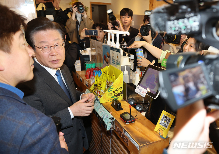 [서울=뉴시스] 권창회 기자 = 이재명 더불어민주당 대표가 23일 오전 서울 성북구 장위2동 카페에서 지역사랑상품권을 이용해 커피를 구입하고 있다.(공동취재사진) 2023.03.23.photo@newsis.com