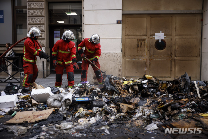 [파리=AP/뉴시스]프랑스 파리에서 24일 소방관들이 연금 개혁에 반대하는 시위로 23일 밤 사이 불탄 쓰레기 더미들의 잔불을 정리하고 있다. 에마뉘엘 마크롱 프랑스 대통령 집무실은 이날 프랑스에서 계속되고 있는 대규모 파업과 시위 속에 찰스 3세 영국 국왕의 프랑스 국빈방문이 연기됐다고 밝혔다. 2023.3.24.