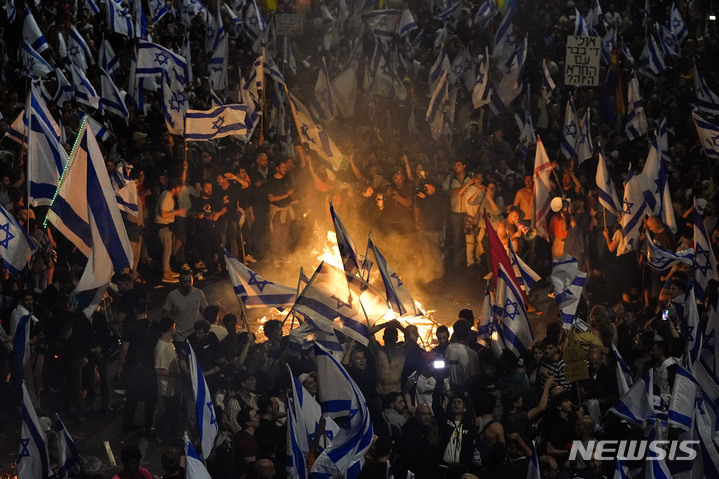 [텔아비브=AP/뉴시스]이스라엘 정부의 사법 개편 추진에 반대의사를 표명한 요아브 갈란트 국방장관을 벤야민 네타냐후 총리가 26일(현지시간) 해임했다는 소식이 전해지자 사법 개편에 반대하는 시위대들이 격렬한 심야 시위를 벌이고 있다. 2023.3.26.