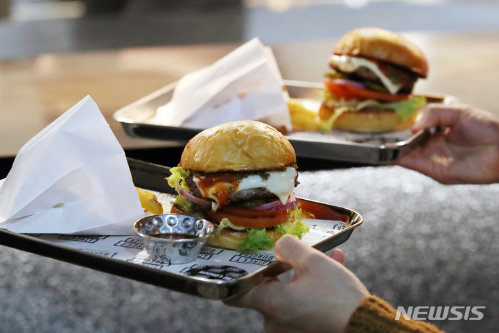 [서울=뉴시스] 조성우 기자 = 27일 오후 서울 강남구 현대백화점 무역센터점에 개점을 하루 앞둔 고든램지 스트리트 버거 매장에서 열린 미디어행사에서 참석자가 버거를 받아 들고 있다. 2023.03.27. xconfind@newsis.com